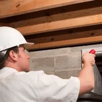 Termite inspection technician checking a basement wall and framing for termite activity in San Jose, CA